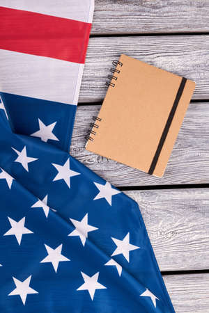 American flag and spiral paper notebook. National flag of USA on vintage wooden background. Paper notepad with binder.の写真素材