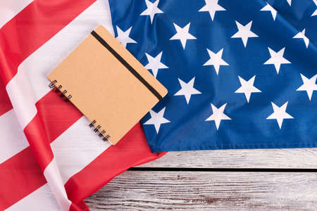Flag of USA, notepad and copy space. American patriotic flag and paper notebook on wooden background.の写真素材