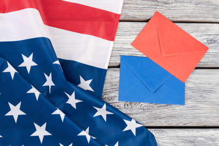 USA flag and colorful envelopes. National flag of America, blue and red envelope on wooden background, top view.の写真素材