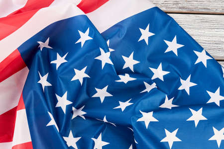 Close up crumpled flag of USA on wood. American flag on vintage wooden boards. Symbols, history,...