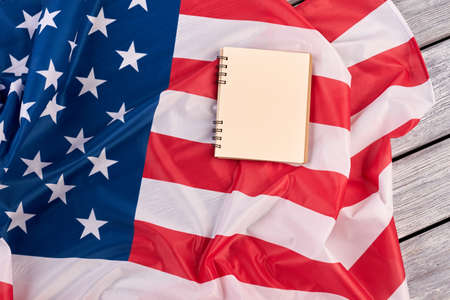 Blank paper notepad on USA flag. Opened notebook and USA flag on wooden boards, top view.の写真素材