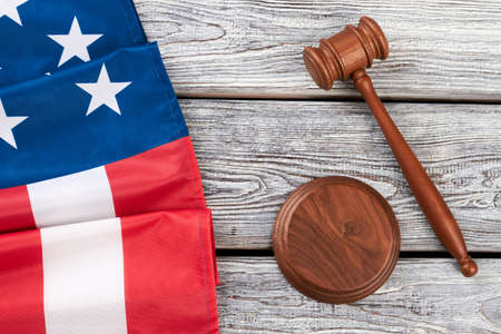Border from American flag and wooden gavel. Justice gavel and folded flag of America on rustic wooden boards, top view.の写真素材