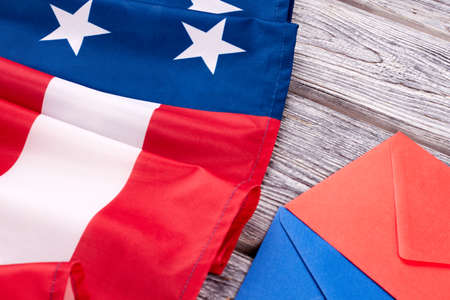 Close up American flag and envelopes. USA national flag and two colorful envelopes on wooden boards.の写真素材