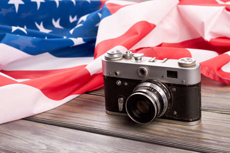 Retro camera and USA flag. Old film camera and American flag on wooden background close up.の写真素材
