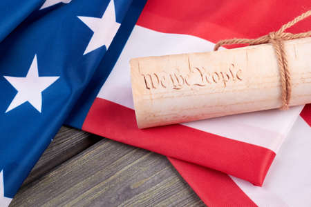 Close up USA flag and document. Rolled-up document and American flag on wooden background close up....