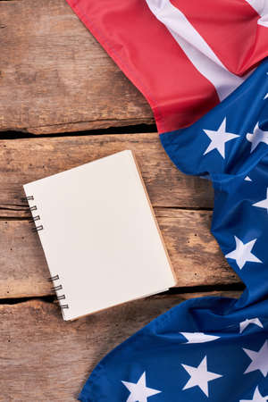 USA flag and notepad, vertical image. Crumpled flag of America and notebook on old wooden boards.の写真素材