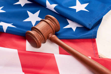 Close up wooden gavel and American flag. Judge gavel and flag of United States of America. Law and justice.の写真素材