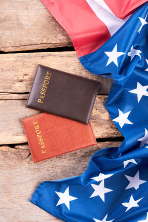 Satin flag of USA and two passports. Passports and flag of United States of America on rustic wooden boards, top view.の写真素材