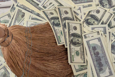 Money as garbage concept. Broom sweeps pile of dollars.の写真素材