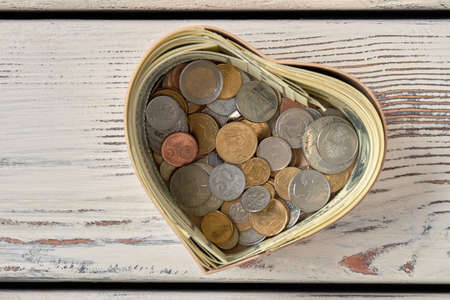 Pile of coins in moneybox. Heart-shaped form for saving cash money. Top view.の写真素材