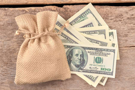 Notes of one hundred dollars and woolean bag. Top view. Wooden desk background.の写真素材