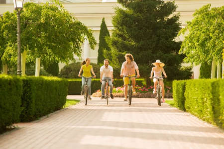 Best friends having fun on bikes. Group of young active students riding bicycles outside. People,...