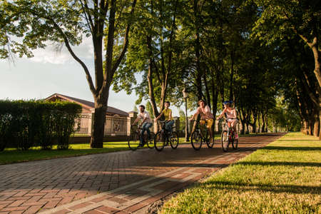 Group of joyful friends riding bikes. Students cycling outdoors. Summe tourism concept.の写真素材