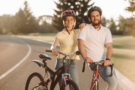 Happy carefree couple with bicycles outdoors. Happy couple standing with bicycles on the road and...