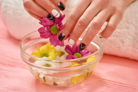 Spa treatment for female hands. Young woman beautiful hands with black and white manicure in spa salon.の写真素材