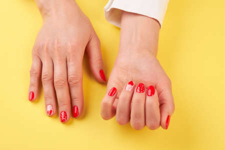 Female hands with creative nail design. Woman beautiful hands with fresh manicure on yellow background. Valentines day nail art design.の写真素材