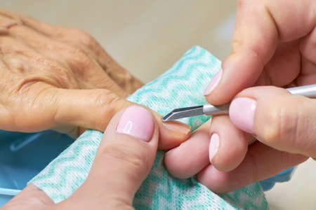 Manicurist cut the cuticle to the client. Nail beautician cutting the cuticle using cuticle scissors. Manicure and skincare.の写真素材
