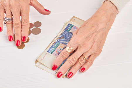 Kyat money and caucasian businesswoman hands. Burma traditional currency well-groomed hands of businesswoman. Myanmar money on white wooden background.の写真素材