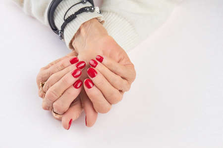 Well-groomed female hands with red manicure. Old woman hands with perfect red manicure isolated on white background.の写真素材
