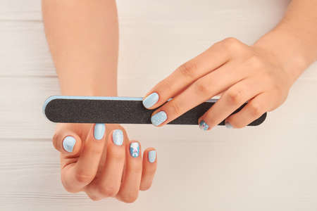 Woman hands filing nails to herself. Manicured hands polishing nails with nail file. Well-groomed...