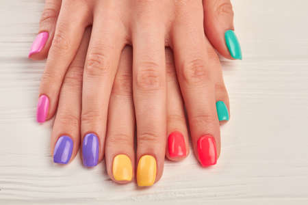 Young woman hands with colorful nails. Colorful nail polish on well-groomed woman hands close up. Nail treatment and spa.の写真素材