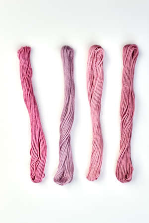 Row of pink color threads, top view. Colorful embroidery threads in bunches isolated on white...