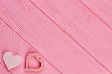 Pink hearts on wooden textured background. Pastel color hearts on pink wood with copy space. Valentines Day greeting card.の写真素材