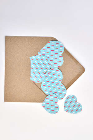 Love letter envelope with paper hearts. Opened envelope from craft paper and blue paper hearts, top view. Happy Valentines Day concept.の写真素材