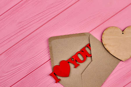 Valentines Day wooden background. Vintage style envelope with wooden heart and text I love you, copy...