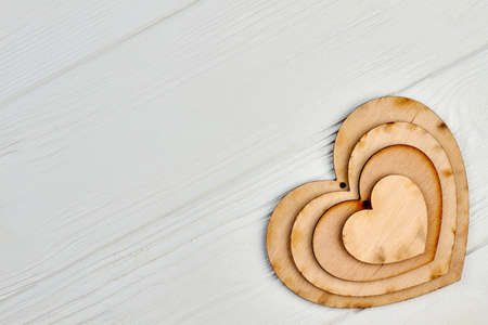 Heart shaped wooden cutouts on light wood. Set of plywood hearts with hole and copy space. Idea for party decoration.の写真素材