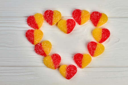 Shape of heart from colorful jelly candies. Colorful candies forming heart shape on white wooden background.の写真素材
