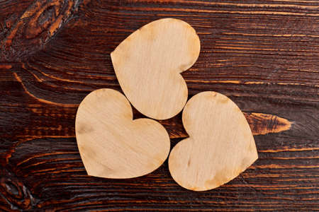 Three wooden hearts, top view. Vintage style wooden hearts on dark wooden background. Valentines holiday greeting card.の写真素材