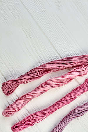 Four bunches of threads for embroidery. Thread bundles set for embroidery on white wooden background and copy space, top view.の写真素材