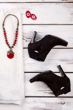 Pair of black suede heel boots. Woolean sweater, necklace with ruby. Talisman earrings.の写真素材