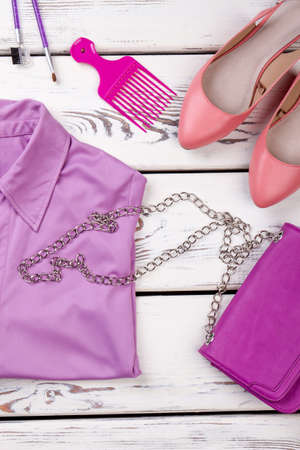 Purple purse with chain handle. Violae shirt, comb. Pink high heel shoes, top view.の写真素材