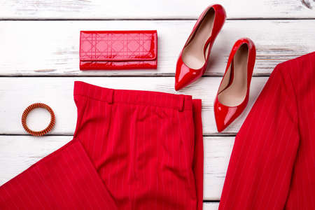 Close up red high heel shoes, clothes and accessories. Bright wooden desks surface background.の写真素材
