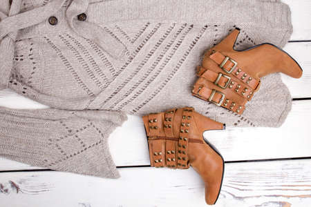Flat lay close up brown heel boots and woolen coat. Brigh wooden background.の写真素材