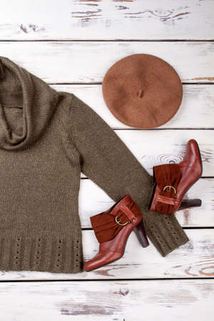 Warm winter female outfit. Green women sweater and pair of leather shoes and brown berete hat.の写真素材