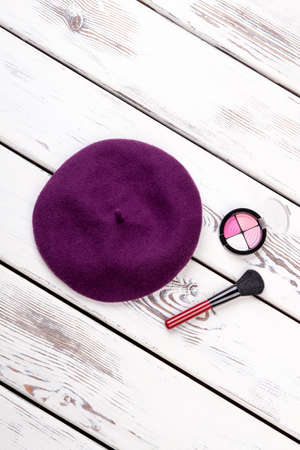 Flat lay purple hat, top view. Violet beret hat, cosmetic brush and powder.の写真素材