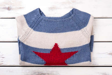 Folded warm knitted sweater, flat lay. White wooden desks surface background.の写真素材