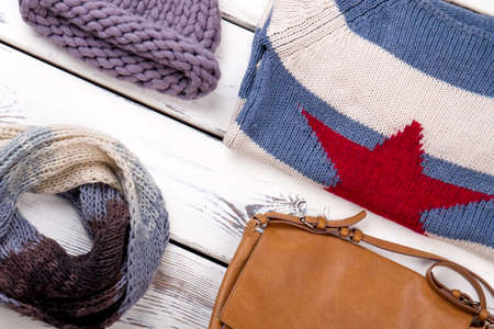 Close up female winter outfit. White wooden desks surface background.