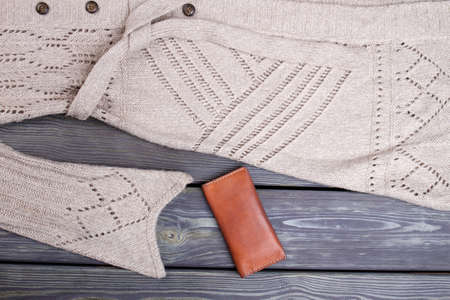 Beige wool clothes and wallet. Close up brown leather billfold.
