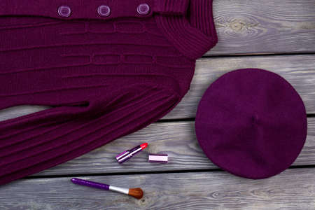 Top view purple winter clothes and cosmetic for make up. Wooden desk surface background.の写真素材