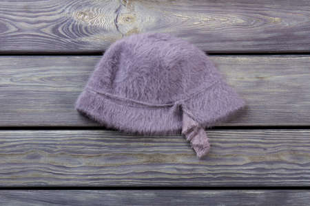 Woolen hairy purple hat. Flat lay, wooden desk surface background.の写真素材