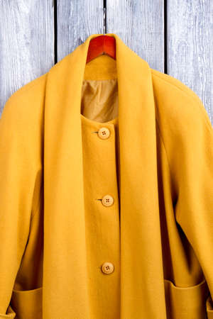 Close up yellow winter coat. Flat lay, top view. Black wooden desk surface background.の写真素材