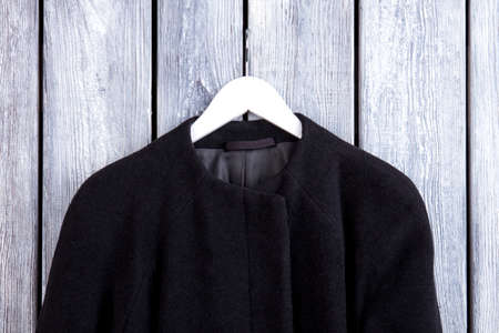 Close up black cashmere coat on hanger. Wooden desk background.の写真素材