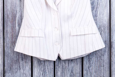 Close up white striped clothing. Bottom of womans jacket. Top view, wooden desk surface background.の写真素材