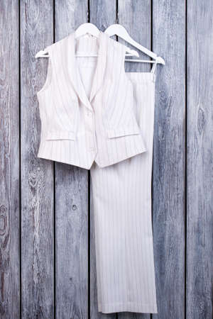 White business outfit. Female business suit with trousers. Dark wooden surface background.の写真素材