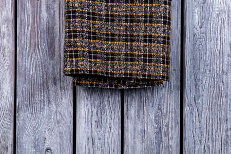 Checkered cloth material, extreme close up. Dark wooden desk surface background.