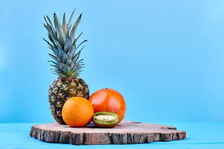 Composition of tropical fruits on natural wood. Fresh pineapple, grapefruit, orange and kiwi fruit...